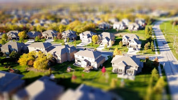 pexels-photo-1546168-1546168 Tilt-shift aerial photo of a suburban neighborhood with green lawns and roads.